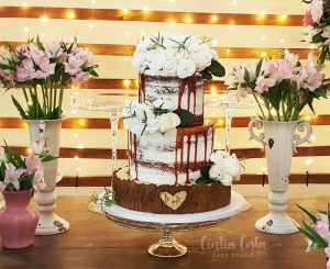 Bolo de casamento naked cake com flores e caramelo escorrido. Feito por Cíntia Costa Cake Studio.