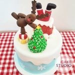 Bolo decorado de Natal: Papai Noel entalado na chaminé, árvore de Natal, rena, presentes e neve. Feito por Cake Studio ( contato@cakestudio.com.br )